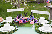 Table festively set for afternoon coffee with luxuriant Easter flower arrangement