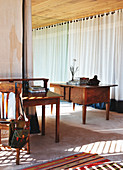 Antique table in front of windows with floor-length curtains