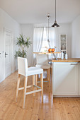 Semicircular breakfast bar on end of kitchen counter in white kitchen of converted dairy