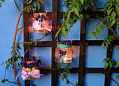 Handmade candle lanterns decorated with lavender hung from trellis