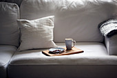 A plate and a cup on a tray on a sofa