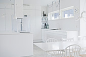 Dining table and island counter in completely white kitchen