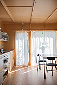 Küche mit Holzverkleidung und weißen Vorhängen an der Terrassentür