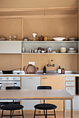 Simple kitchen in brown and grey with crockery in earthy tones