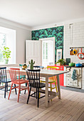 Bunte Windsorstühle um den Esstisch in der Küche mit Holzboden