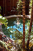 Blick auf Pool in exotischem Garten, Beine ragen aus dem Pool