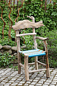 Rustikaler Stuhl aus Treibholz mit bunt gewebter Sitzfläche
