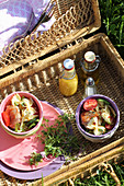 Pasta salad and small swing-top bottles in open picnic basket