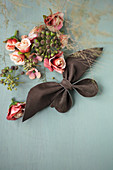Leather bow, fabric flowers and ivy berries on grey surface