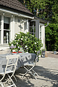 Gartentisch auf der Terrasse vor dem weißen Schwedenhaus