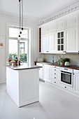 Island counter and stucco ceiling in white country-house kitchen