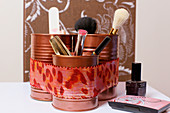 Makeup brushes in organiser made from painted tin cans