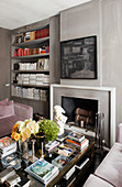 Coffee table in front of open fireplace and fitted shelves in grey wall