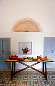 Plates of fruit on rustic wooden table on Mediterranean patterned tiled floor