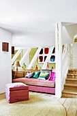 Pink sofa with colourful scatter cushions next to foot of stairs