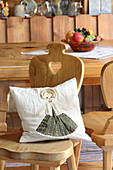 Cushion with appliqué doll motif on rustic wooden chair