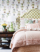 Doppelbett mit hohem Bettkopfteil und Nachtkästchen an tapezierter Wand
