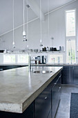 Concrete worksurface on island counter in front of tall narrow window