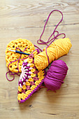 Granny squares crocheted from pink and yellow jersey yarn and reels of yarn