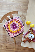Cushion with crocheted jersey cover on chair at breakfast table