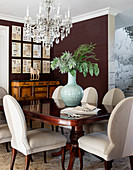 Antique table and elegant upholstered chairs below chandelier