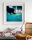 Designer lamp on marble shelf, photo art above, rattan chair in foreground