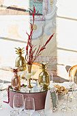 Mirrored pedestal with vase, candles and golden pineapple on festively set table