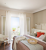 Bedroom in muted shades with open door leading to balcony