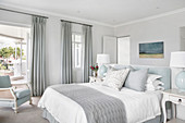Elegant bedroom in pale blue-grey with partition wall at head of bed