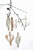 Pendants made from strips of paper hung from twig against white background