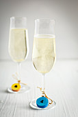 Colourful tags made from corks on two glasses of sparkling wine