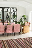Upholstered chairs around dining table in front of three large mirrors with pattern of circles