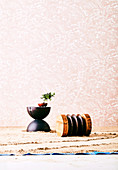 Designer stool in wood on sandy floor in front of pink wallpaper