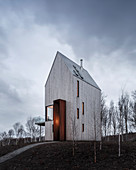 Modernes Haus mit Holzfassade und vertikalen Fenstern auf einem Hügel