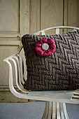 Cushion with knitted cover and knitted flower on chair