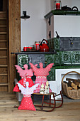 Hand-sewn Christmas angels on sledge in front of tiled stove
