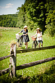 Two girls pushing bicycles with picnic baskets