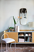 Pink metal chair in front of sideboard with open-fronted compartments