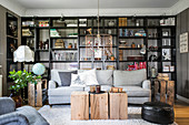 Grey couch, wooden block used as coffee table and floor-to-ceiling bookshelves in living room