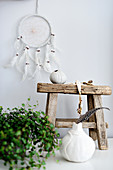 White dreamcatcher above small wooden stool and Bohemian ornaments