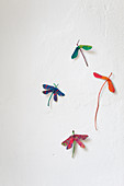 Dragonflies made from painted sycamore seeds on white wall