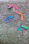Dragonflies made from painted sycamore seeds on wood