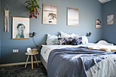 Doppelbett und großformatige Fotos im Schlafzimmer mit grau-blauen Wänden