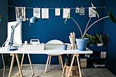 White table top on wooden trestles in study with deep-blue walls