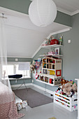 Doll house, shelves, toy box, grey walls and sloping ceiling in girl's bedroom