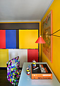 Desk and multicoloured chair in study with yellow wall and colourful wall panels
