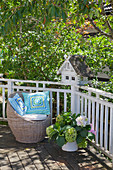Blue-and-green cushions on round wicker chair on balcony