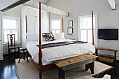 Four-poster bed and old benches in bedroom with exposed roof structure