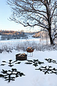 Decoratively arranged pine branches and fire bowl in snowy landscape
