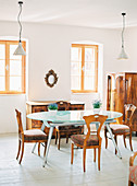Modern dining table with glass top and Biedermeier furniture in bright dining room